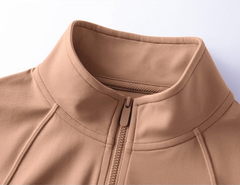 Close-up of a women's beige fitness sports sweatshirt with a zippered front and high collar.